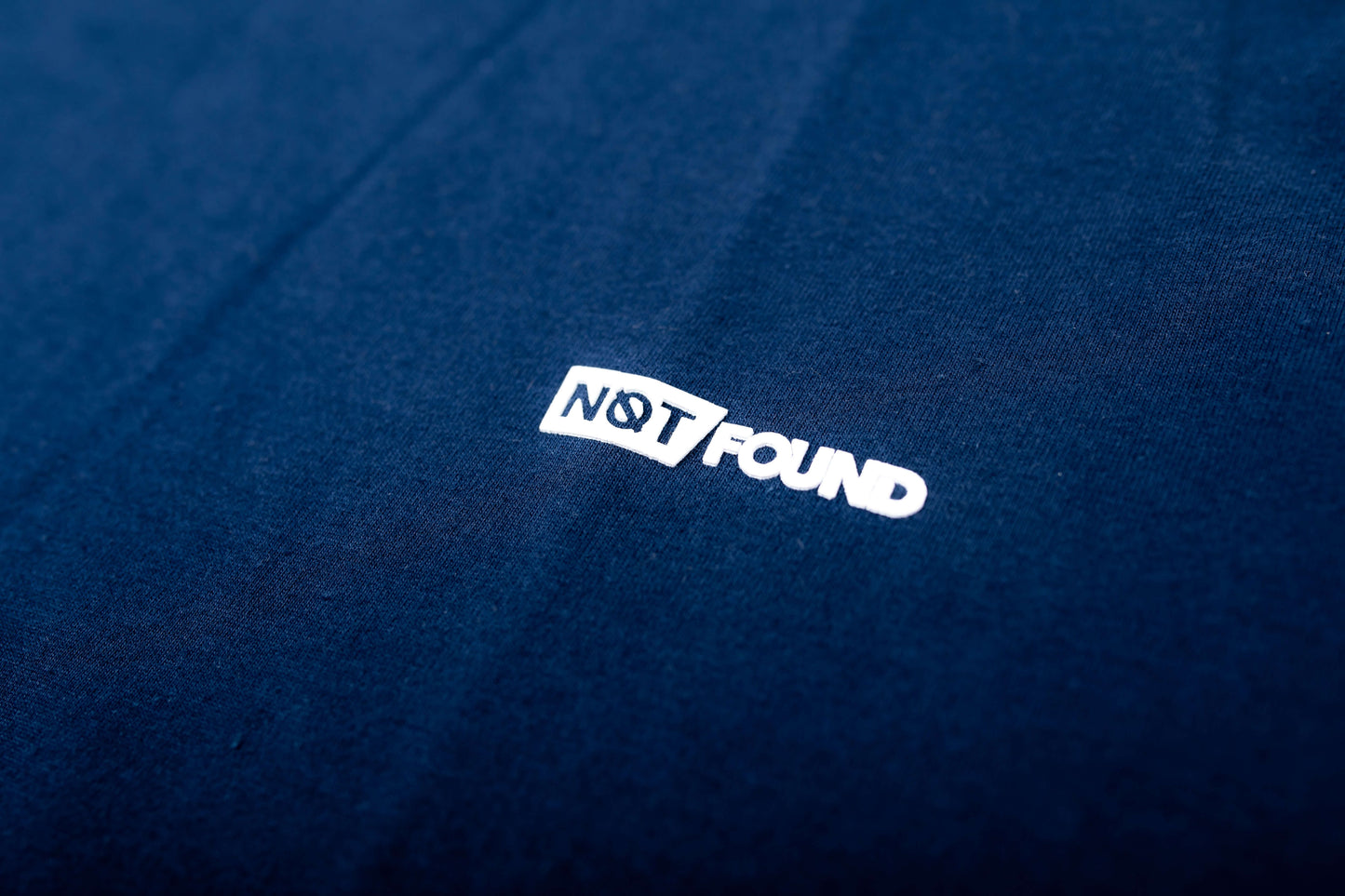 Polera Urban Regular azul marino con etiqueta "NOT FOUND" en un fondo de tela suave de algodón.