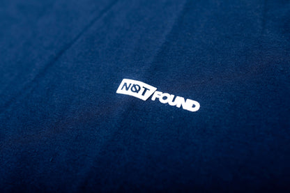 Polera Urban Regular azul marino con etiqueta "NOT FOUND" en un fondo de tela suave de algodón.